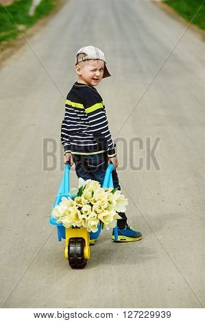 boy stands in the road with a bouquet of flowers