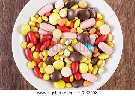 Colorful medical pills tablets capsules or supplements for therapy on plate concept of treatment and health care