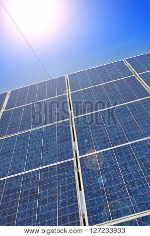 Solar panel with bright sun on a blue summer sky