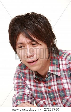 portrait of sad young Japanese man on white background