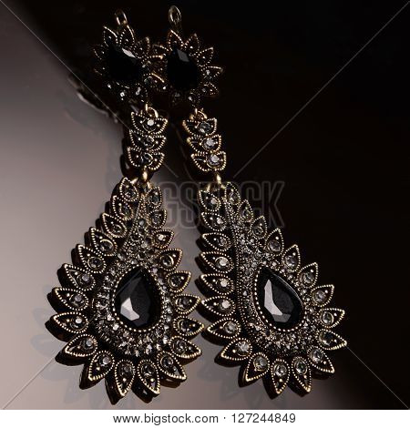 silver earrings with black stones on dark glass