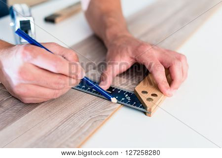 Carpenter marking cut on parquet piece 