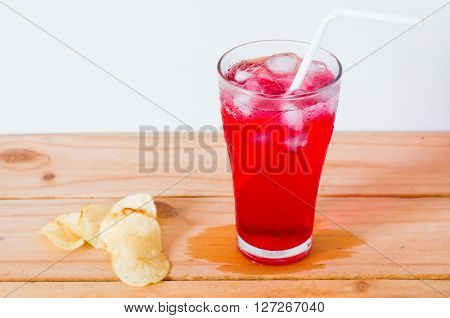 red drinks with soda and ice in glass with straw and fired potato on wooden background