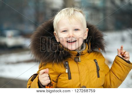 Close up portrait, little baby blonde boy in a winter park