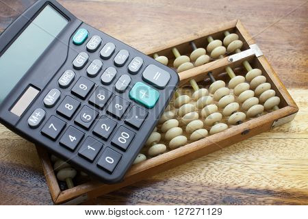 Abacus and calculator with wooden table background