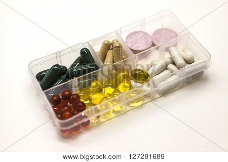 Different pills, medications, the pills in the daily drug medicine organiser drugs closeup on white background.