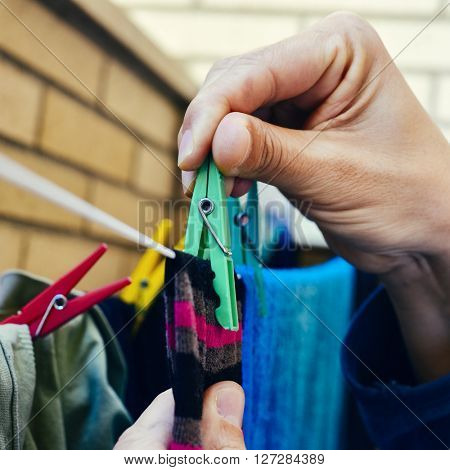 closeup of a young caucasian man hanging up some clothes with clothespins in a clothes line