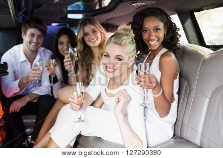 Happy friends drinking champagne in limousine