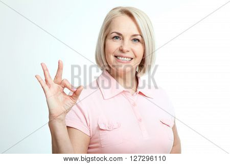 Smilling attractive middle aged woman showing thumbs up, okay. Isolated square