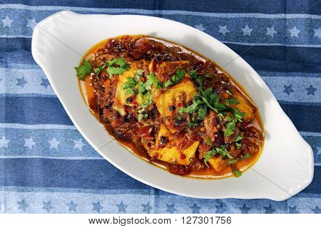 Kadhai Paneer in a white container on a blue background with copy space selective focus.