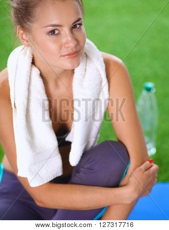 Beautiful young woman relaxing after exerscises on the grass