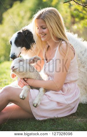 Young blonde woman outdoor portrait with lamb and russian wolfhound dog. Life at the farm.