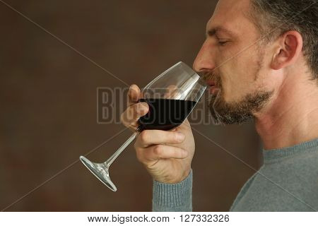 Handsome middle-aged man tasting red wine, close-up