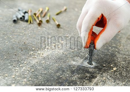 Worker put a plastic dubel in the concrete floor.