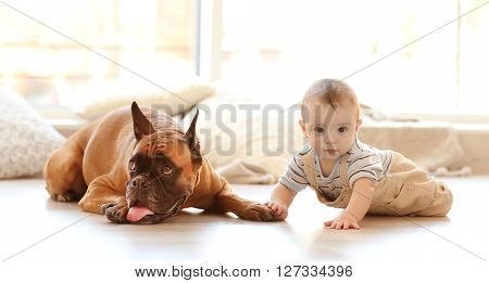 Little baby boy with boxer dog lying on the floor at home
