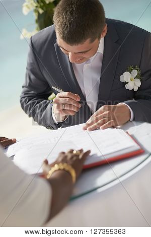 Gorgerous Wedding Couple Putting Their Signatures In Marriage Certificate During Ceremony.