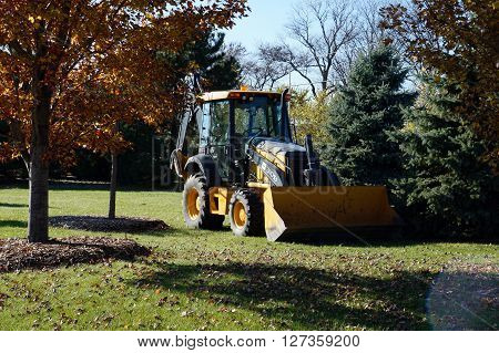 NAPERVILLE, ILLINOIS / UNITED STATES - NOVEMBER 3, 2015: A John Deere 310SJ backhoe sits parked in the Naperville Park District's Wildflower Park.