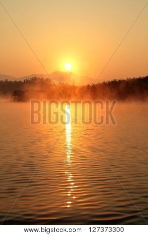 Misty tropical sunset on lake with wooden house in Mae Ngad Dam and Reservoir Chiang Mai Thailand
