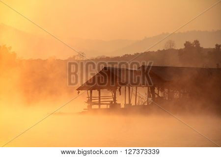Misty tropical sunset on lake with wooden house in Mae Ngad Dam and Reservoir Chiang Mai Thailand
