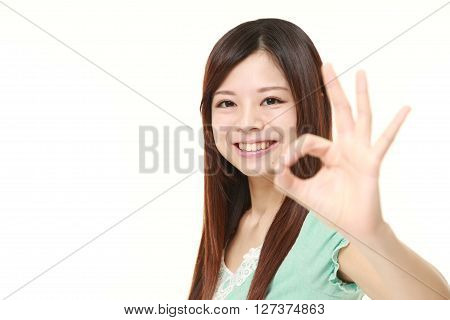 young Japanese woman showing perfect sign on white background