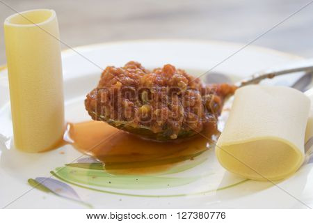 traditional kind of pasta of gragnano called paccheri with a spoon of tomato sauce
