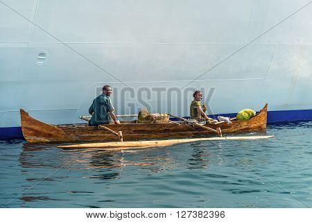 Hell-Ville Madagascar - December 19 2015: Malagasy vendors from their outrigger canoe offer crabs fish and tropical fruits to ship passengers at Hell-Ville Nosy Be Island Madagascar.
