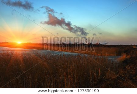 power plant on the background of the pond with reeds at sunset. pollution.