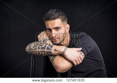 Handsome and stylish young man with black t-shirt. Cool tattoos on arms