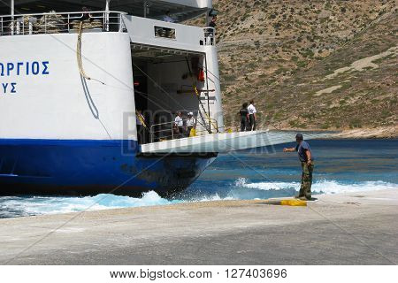 ISLAND OF SIFNOS, GREECE - AUGUST 24, 2007: Dock worker is pulling a rope while ship crew is standing on a docking platform of approaching ferry Agios Georgios, Ventouris Sea Lines.