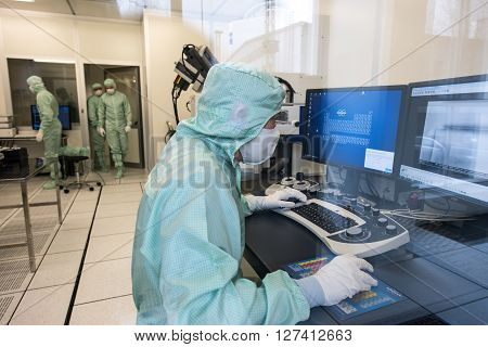 Saint-Petersburg Russia - April 18 2016: Engineer in microelectronics clean room behind the glass in the process. The company for the production of precision electronic circuits and devices.