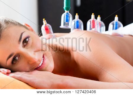 Woman in alternative medical cupping therapy with cups being applied on her back