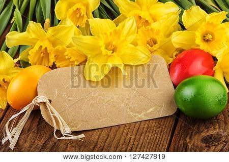 Easter decoration with daffodil flowers and eggs. Paper label with copy space.