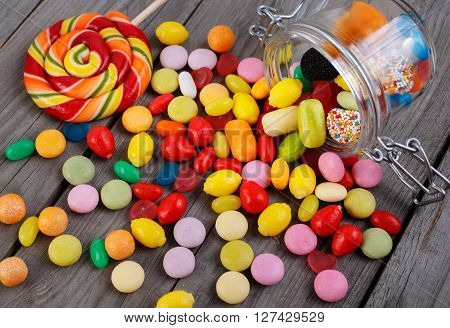 Colorful candies in jar on wooden table with copy space. Candies scattered on the wooden table