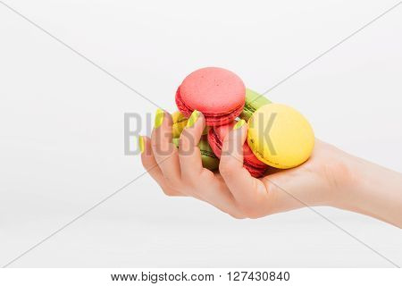 Person holding many different  macaroons in her hand