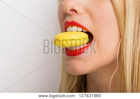Pretty and beautiful woman eating yellow macaroon cookie