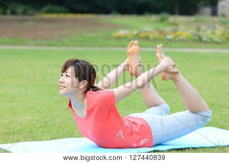 Japanese woman outside doing yoga bow pose