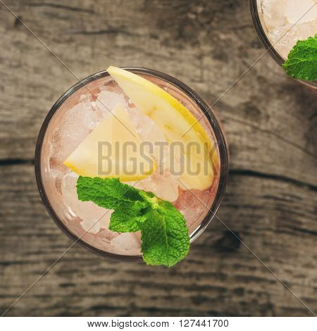 Summer cocktail with ice lemon apple and mint on dark wooden background top view