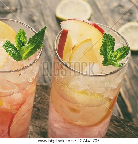 Two cocktail with ice mint lemon and apple in tall glass loseup on dark wooden background. Summer refreshing cocktails