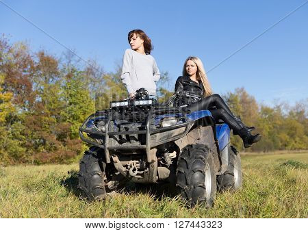 Two elegant women riding extreme quadrocycle ATV