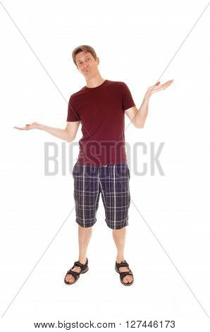 A young man in a burgundy t-shirt and shorts standing relaxed with his arms raised and giving up isolated for white background.
