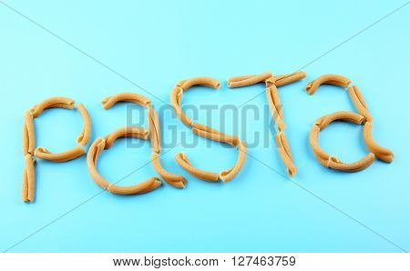 Pasta word made of casarecce on turquoise background