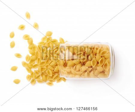 Glass jar filled with dry conchiglie yellow pasta over isolated white background