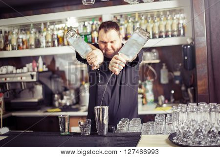 Barman hold bottle and pouring cocktail at the bar
