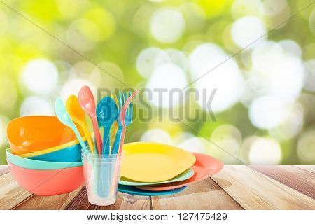 Colorful Plastic tableware picnic set on wooden plank table with summer sea and blue sky blurred background
