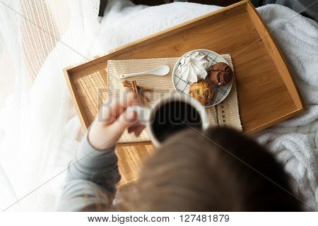 Sweet breakfast in bed served on tray with coffee and cupcakes
