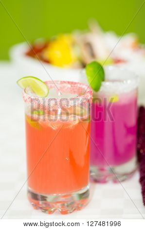 Closeup small sugarcoated shotglasses with delicious orange and purple juices inside.