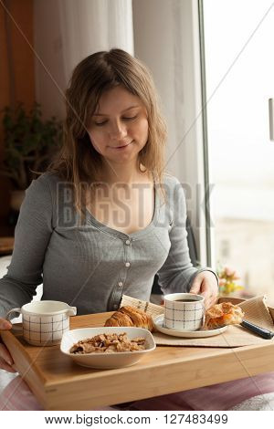 Healthy breakfast in bed served on tray with coffee, cornflakes, croissant and milk