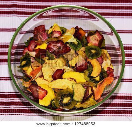Dried fruit in glass and metallic dishes on wooden ground