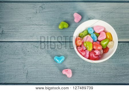 Colored pills in a circular plate on a wooden background.
