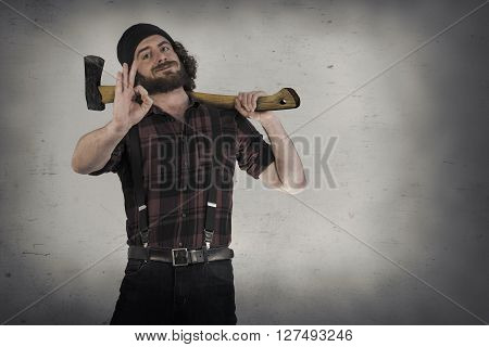 Silly hipster lumberjack gives okay sign while holding axe